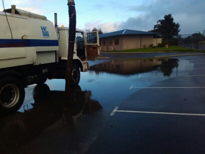 A soakwell cleaning trucks sits in a flooded carpark.