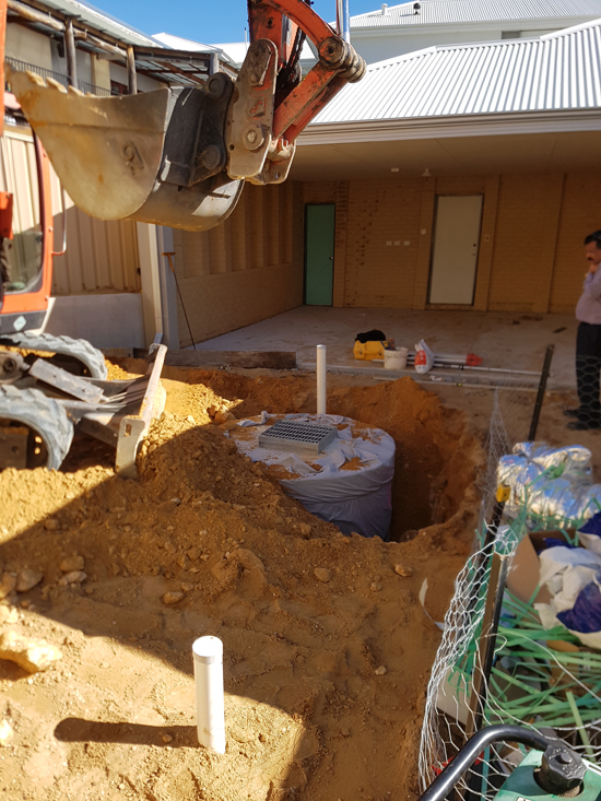 Concrete soakwell with grate installed in driveway.