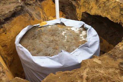 Concrete soakwell being installed by excavator.